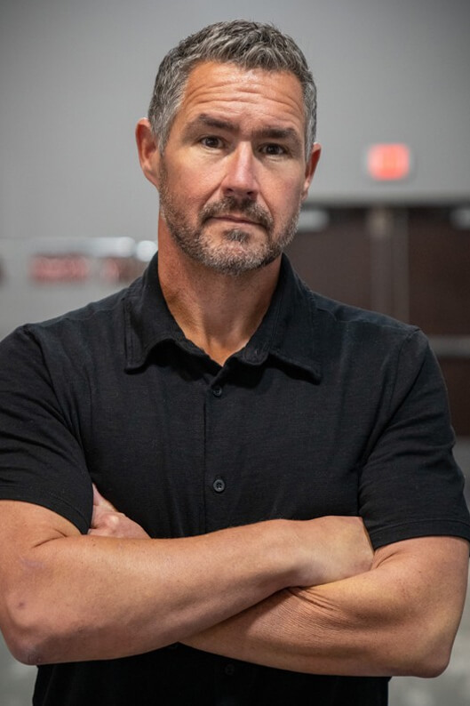 man wearing a black golf shirt with arms crossed